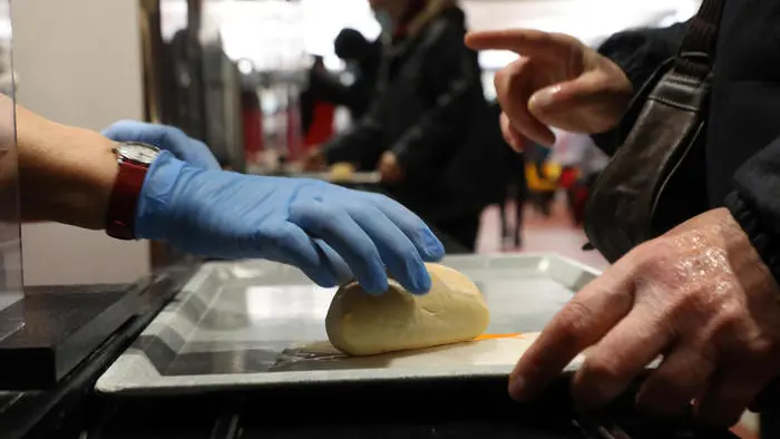 Persone in fila in una mensa Caritas per un pasto caldo