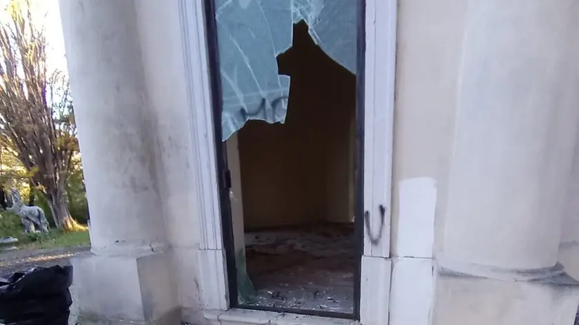 Una delle vetrate deturpate dalle scritte e sfondate