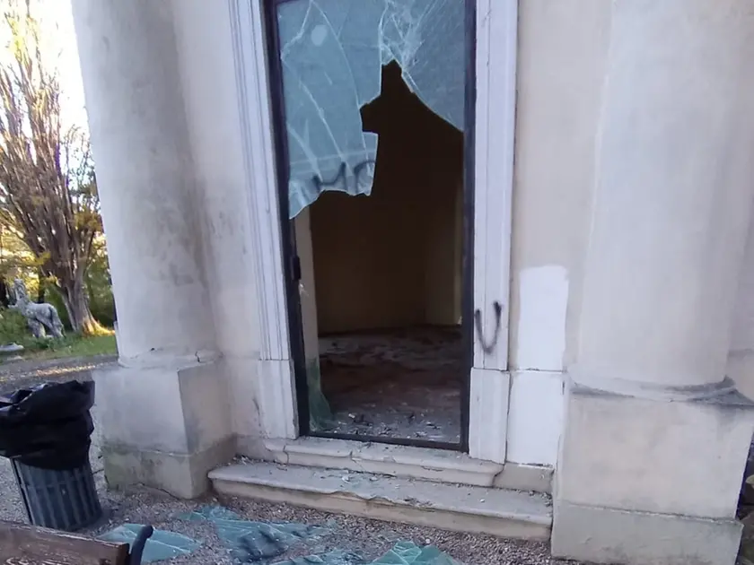 Una delle vetrate deturpate dalle scritte e sfondate