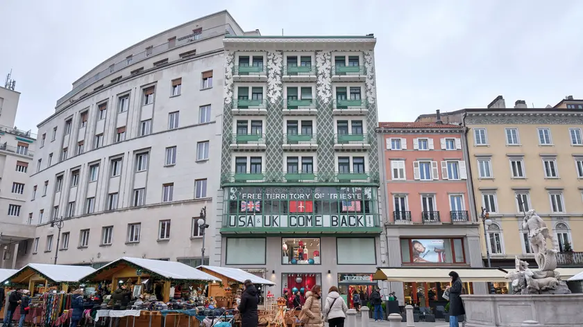 Il palazzo liberty di piazza della Borsa dell’architetto Max Fabiani con striscioni e bandiere Foto Silvano