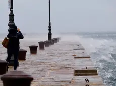 Il molo Audace bagnato dalle onde provocate dalla bora il giorno della vigilia di Natale mentre una coraggiosa immortala il paesaggio. Foto Silvano