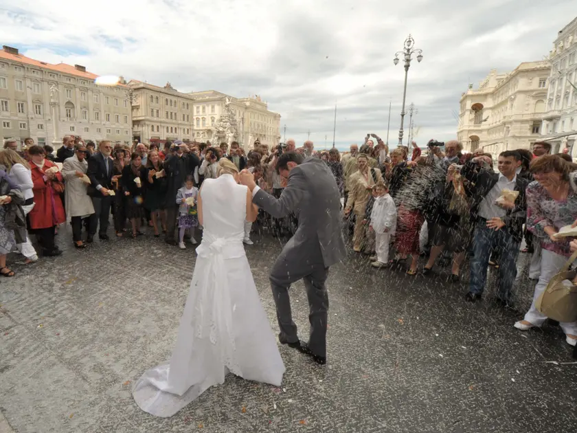 Pioggia di riso su una coppia di sposi in piazza Unità