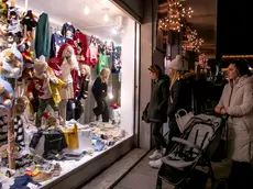Clienti davanti a una vetrina in centro, sullo sfondo le luminarie di Natale (Bonaventura)