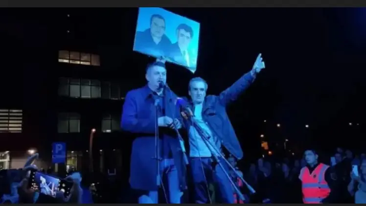 Malić in piazza che mostra la foto di Karadžić e Mladić con il gesto serbo delle tre dita in segno di vittoria