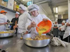 Una cuoca al lavoro in una cucina mentre prepara un piatto