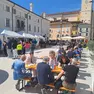 La gente seduta sulle panche della piazza dopo aver preso il cibo
