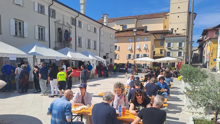 La gente seduta sulle panche della piazza dopo aver preso il cibo
