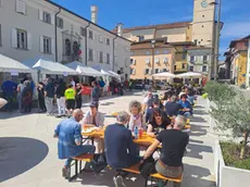 La gente seduta sulle panche della piazza dopo aver preso il cibo
