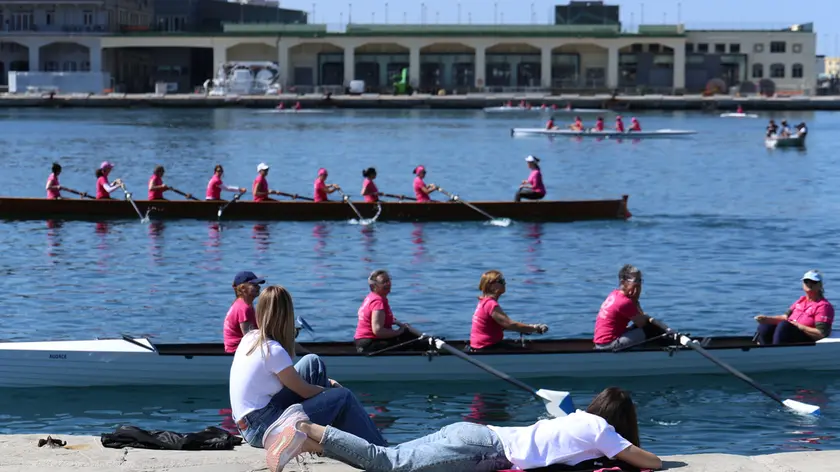 “Fiume in rosa” con le donne pronte a vogare in mare e due ragazze incuriosite sul molo Audace Foto Andrea Lasorte
