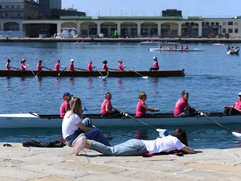 “Fiume in rosa” con le donne pronte a vogare in mare e due ragazze incuriosite sul molo Audace Foto Andrea Lasorte