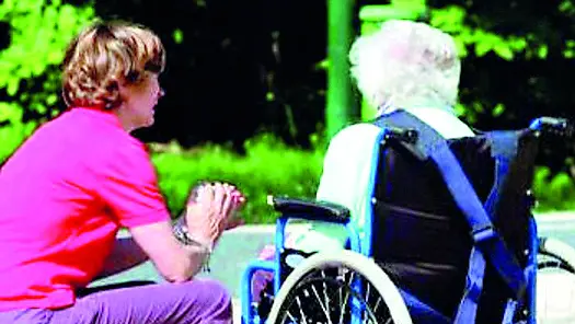 Una badante assiste un’anziana disabile (foto d’archivio)