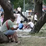 Un uomo seduto sul tronco di un albero osserva un gruppo di bambini che gioca nell'Area verde di Monfalcone. Foto servizio Bonaventura