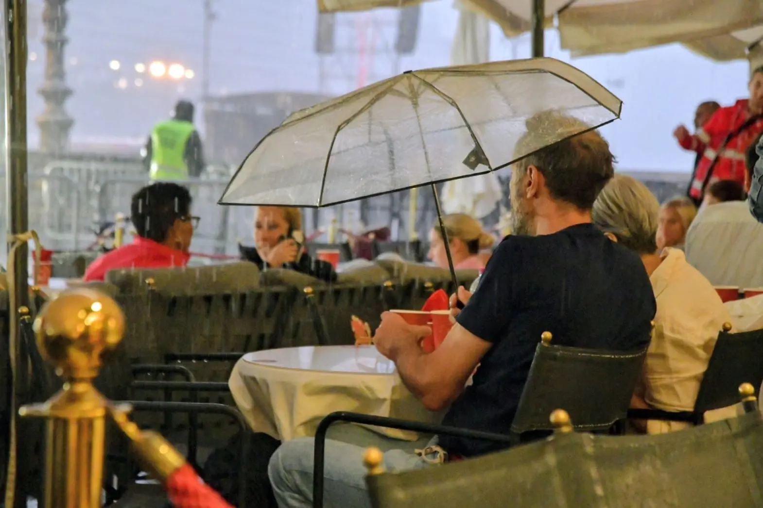 Due spettatori si riparano sotto gli ombrelloni dei bar di piazza Unità