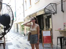Una ragazza cerca refrigerio davanti a un maxi-ventilatore installato fuori da un locale pubblico