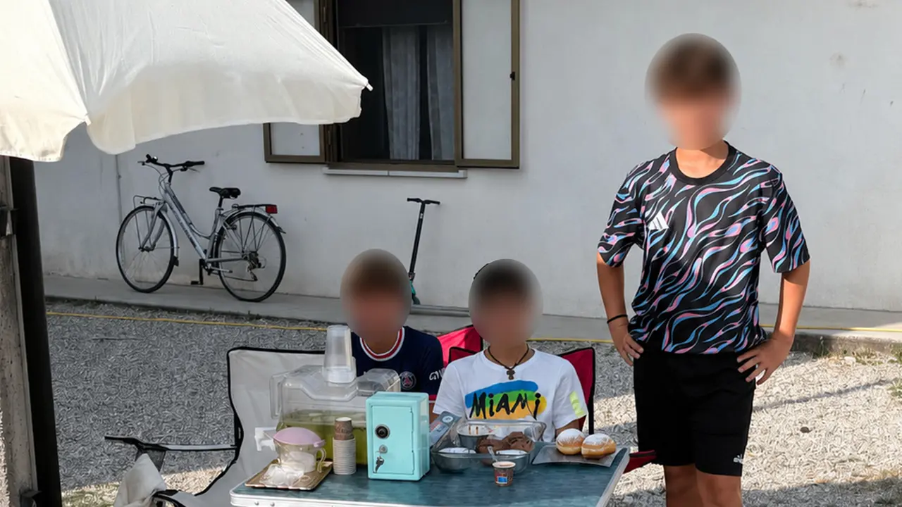 I tre amici dietro al loro banchetto con limonata, caffè e dolcetti