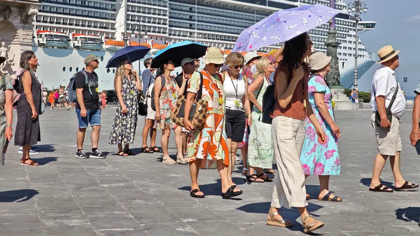 Un gruppo di turisti si protegge dal sole in piazza Unità a Trieste (foto Andrea Lasorte)