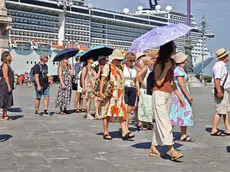 Un gruppo di turisti si protegge dal sole in piazza Unità a Trieste (foto Andrea Lasorte)
