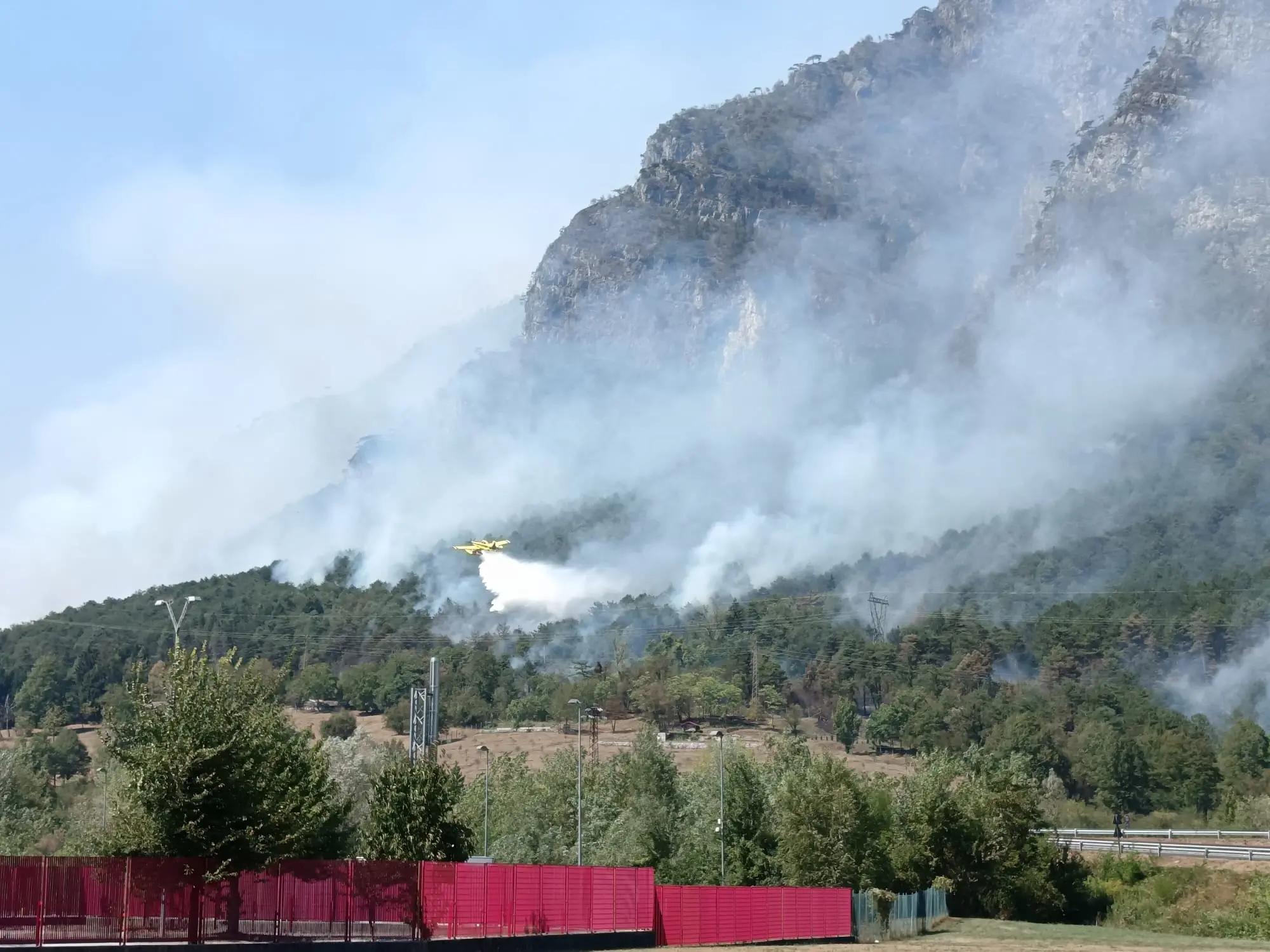 Le colonne di fumo degli incendi che stanno bruciando in Carnia sono visibili a chilometri di distanza e in alcune zone l’aria è diventata difficile da respirare. Una coltre grigia avvolge vallate e montagne, oscurando il cielo e cambiando il volto del paesaggio. Nella notte appena trascorsa, nel buio erano le fiamme sui versanti a illuminare la montagna, mentre con il giorno il fumo è tornato a dominare lo scenario.