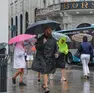 Alcuni passanti con ombrello e mantellina venerdì pomeriggio a Trieste (foto Andrea Lasorte)