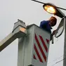 Un operaio al lavoro su un palo dell'illuminazione.