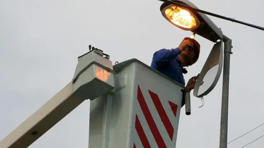 Un operaio al lavoro su un palo dell'illuminazione.