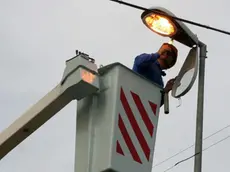 Un operaio al lavoro su un palo dell'illuminazione.