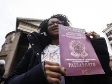 Una donna esibisce un cartello a favore della concessione della cittadinanza