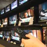 Un utente con il telecomando davanti ai televisori