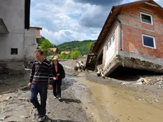 epa04213600 A picture made available 19 May 2014 shows people passing by damaged houses after flooding in Krupanj, 150 km southeast of Belgrade, Serbia, 18 May 2014. Clean-up began on 19 May after massive floods in parts of Serbia and Bosnia, even as cities on the river Sava braced for the arrival of a new wave of flooding. The situation was particularly grave in Krupanj, which has been without drinking water and electricity since 14 May, and Obrenovac, near Belgrade that saw the deaths of 12 people as flood waters covered most of the town. EPA/DRAGAN KARADAREVIC