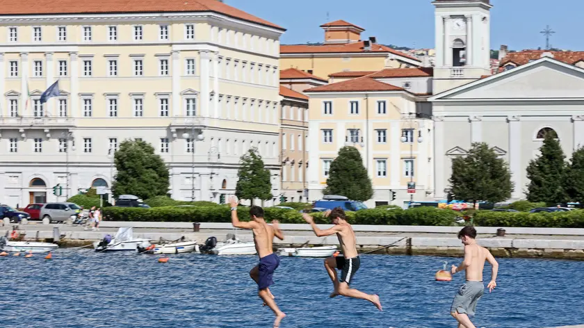 Tre ragazzi si lanciano dal molo Audace (fotoservizio di Andrea Lasorte)