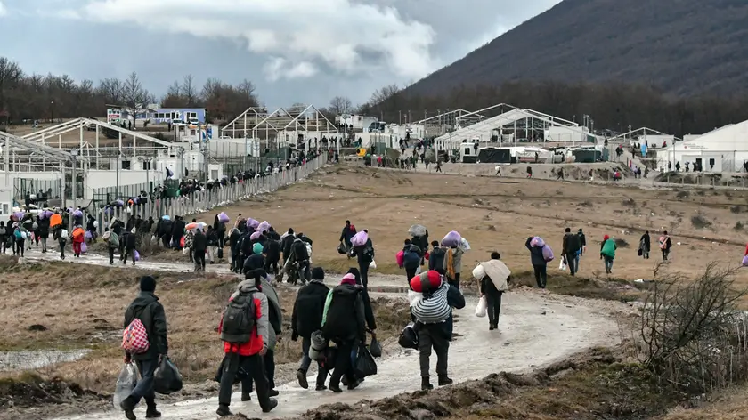 Migrants walk back to the Lipa camp outside Bihac, Bosnia, Wednesday, Dec. 30, 2020, after hundreds failed to be relocated from the burnt-out tent camp in the northwest of the country. The migrants were supposed on Tuesday to be transferred from the much-criticized Lipa camp to a new location in the central part of the country, but have instead spent some 24 hours in buses before being told on Wednesday afternoon to disembark and return to the now empty camp site. (AP Photo/Kemal Softic)