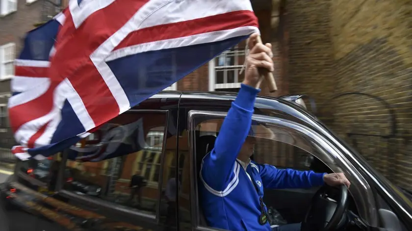 Un tassista londinese sventola la bandiera della Gran Bretagna dopo la vittoria della Brexit