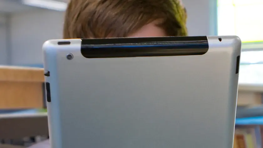 Male student reading electronic book on digital tablet in school library