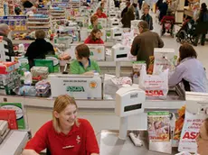 ca. 2004, York, North Yorkshire, England, UK --- Original caption: Smiling worker and a happy customer at the many tills of the Monks Cross ASDA. ASDA was formed by a group of farmers from Yorkshire and now has 265 stores and 19 depots across the UK. It was bought by Wal-Mart in 1999, and in 2004 was the UK's 2nd largest grocery chain. --- Image by © Gideon Mendel/Corbis