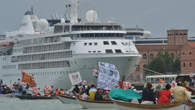 Attivisti del comitato No Grandi Navi in Laguna mentre, a bordo di imbarcazioni a motore, ritardano l'uscita in mare della supernave MSC Divina, navigando in tondo lungo il canale della Giudecca, Venezia, 9 giugno 2013. ANSA/ANDREA MEROLA
