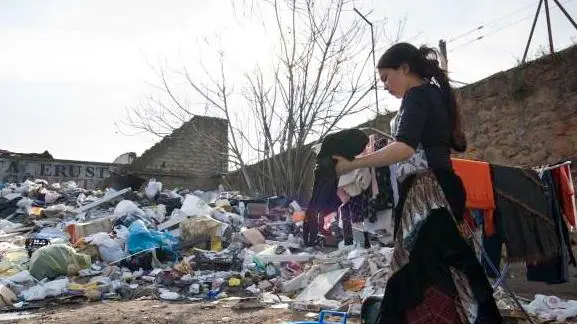 Rome, Lazio, Italy --- A gypsy woman washes some clothes next to a garbage dump in an illegal roma camp. Romanian gypsies evicted from other places, have found this dismissed factory and they settled here. This place is a sort of garbage dump, with rubbish, rats and insects everywhere.This will be their place until police forces will come and pull them away from here. Then they will start serching again for another place. --- Image by © Marco Baroncini/Corbis