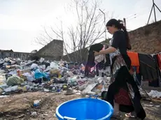 Rome, Lazio, Italy --- A gypsy woman washes some clothes next to a garbage dump in an illegal roma camp. Romanian gypsies evicted from other places, have found this dismissed factory and they settled here. This place is a sort of garbage dump, with rubbish, rats and insects everywhere.This will be their place until police forces will come and pull them away from here. Then they will start serching again for another place. --- Image by © Marco Baroncini/Corbis