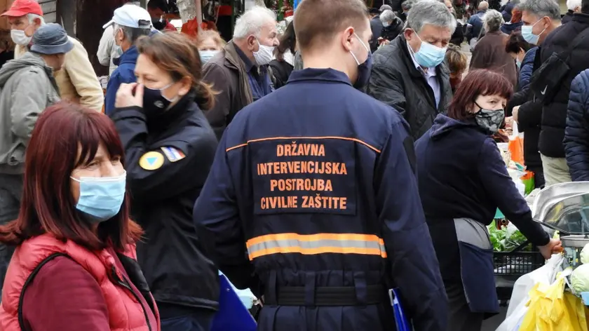 Un operatore della Protezione civile controlla l’uso delle mascherine al mercato ortofrutticolo di Zagabria. jutarnji.hr