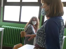 Un’insegnante in classe con la mascherina sul viso