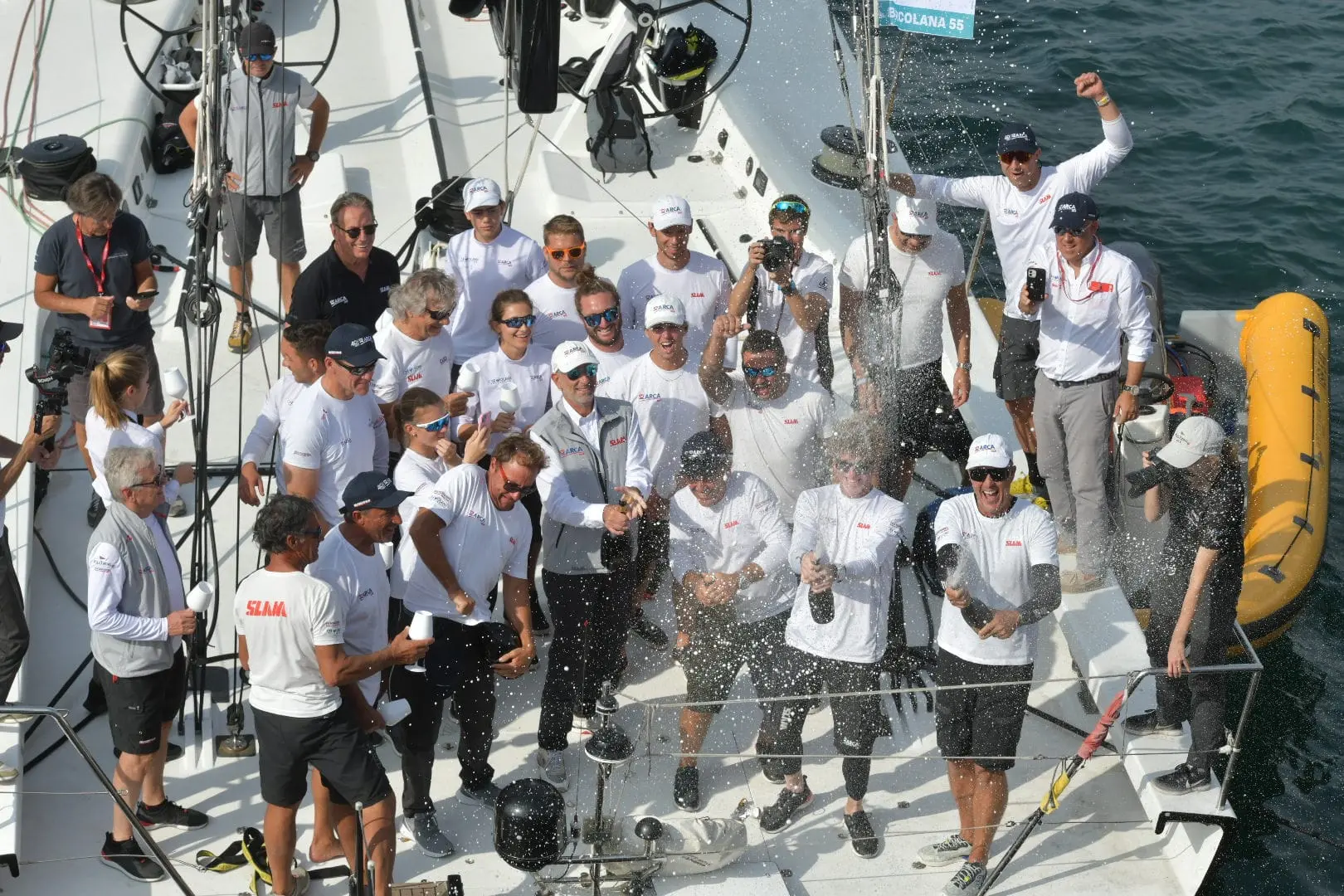 Arca Sgr del velista triestino Furio Benussi, leader del Fast and Furio Sailing Team, ha vinto la Barcolana numero 55 in un'ora 49 minuti e 55 secondi. La regata più grande del mondo questa mattina ha dato spettacolo nel golfo di Trieste con 1.773 vele in partenza in una giornata caratterizzata da pochissimo vento, tanto che la competizione si è chiusa alla prima boa. Al timone di Arca sulla linea di arrivo la giovanissima Marta, figlia di Furio Benussi, di soli 16 anni. Padre e figlia insieme si sono tuffati in segno di festeggiamento dal Molo Audace, dove si sono tenute le premiazioni. A consegnare il trofeo anche il Ministro per lo Sport e i Giovani Andrea Abodi, assieme al Presidente della Barcolana Mitja Gialuz il vincitore. Foto di Andrea Lasorte, Massimo Silvano e Francesco Bruni