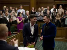 Sean Adl-Tabatabai, left, and Sinclair Treadway are applauded by their guests as they were announced officially married during a wedding ceremony in the Council Chamber at Camden Town Hall in London, minutes into Saturday, March 29, 2014. Gay couples in Britain waited decades for the right to get married. When the opportunity came, some had just days to plan the biggest moment of their lives. Adl-Tabatabai, a 32-year-old TV producer from London, and Treadway, a 20-year-old student originally from Los Angeles, registered their intent to marry on March 13, the first day gay couples could sign up for wedding ceremonies under Britain's new law. Eager to be part of history, the two men picked the earliest possible moment - just after midnight Friday, when the act legalizing same-sex marriage takes effect. (AP Photo/Matt Dunham)