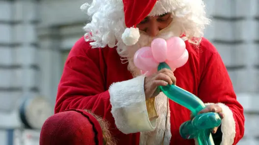 20041222 - ROMA - NATALE : BAMBINA INCANTATA DA BABBO NATALE- Una bambina guarda incantata Babbo Natale che finge di sentire il profumo di un fiore confezionato con palloncini prima di darglielo in dono. GIULIA MUIR /ANSA /JI