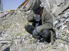 A man helps Ukrainian soldiers searching for bodies in the debris at the military school hit by Russian rockets the day before, in Mykolaiv, southern Ukraine, on March 19, 2022. - Ukrainian media reported that Russian forces had carried out a large-scale air strike on Mykolaiv, killing at least 40 Ukrainian soldiers at their brigade headquarters. (Photo by BULENT KILIC / AFP)