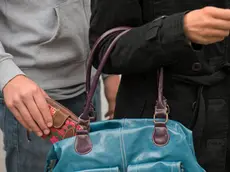 21 Aug 2014, Dresden, Germany --- ILLUSTRATION - A man steals a wallet from a woman's handbag at the streetcar and bus station in Dresden, Germany, 21 August 2014. Photo: ARNO BURGI/dpa --- Image by © Arno Burgi/dpa/Corbis