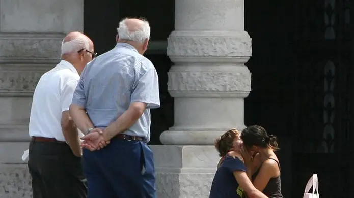 Una coppia di anziani a passeggio e, accanto, due giovani