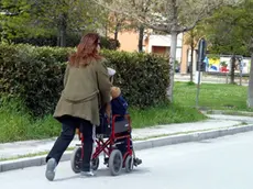 Una badante mentre porta a passeggio un anziano