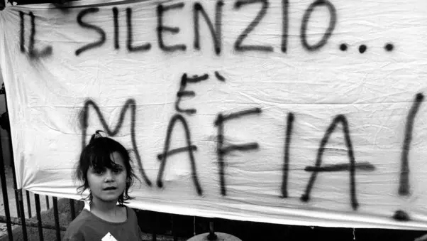 Palermo , September 1993 - Demo against the killing of Father Puglisi - A female child in front of a banner with the writing " Silence is Mafia " <> Palermo , settembre 1993 - Protesta contro la mafia per l'uccisione di Padre Pugliesi - Una bambina di fronte ad uno striscione con la scritta " Il silenzio mafia " *** Local Caption *** 00127716