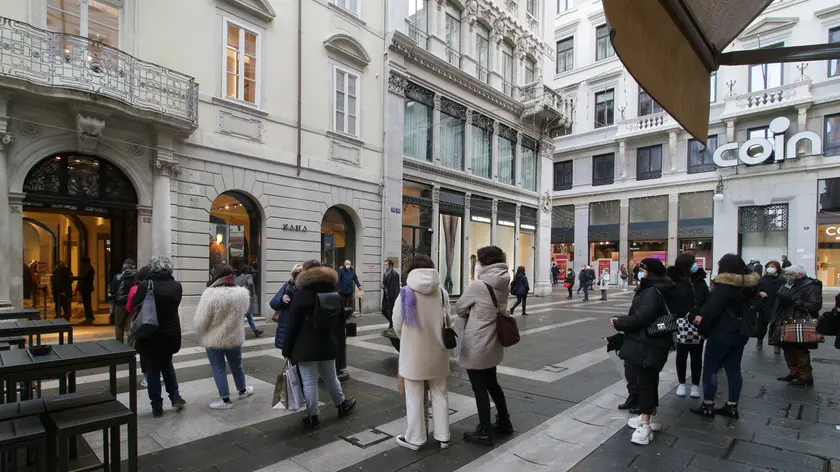 Persona in fila davanti a un esercizio a Trieste. Foto di Andrea Lasorte