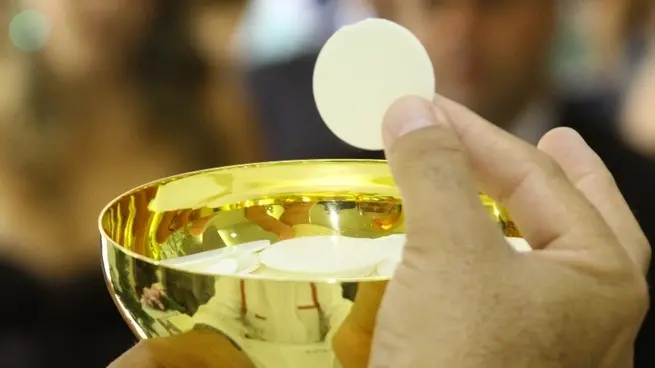 Un parroco porge le particole consacrate ai fedeli