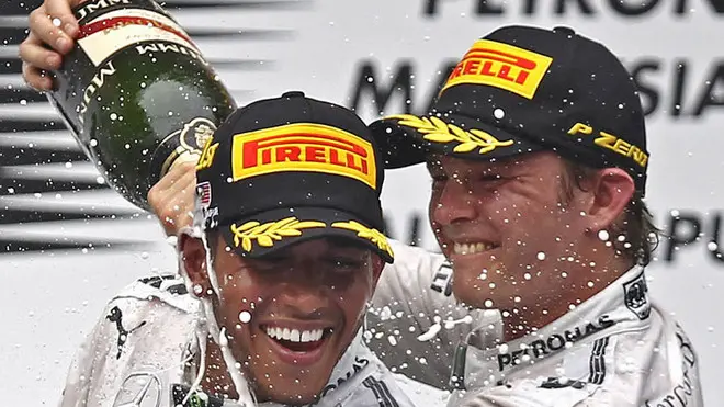 Mercedes driver Lewis Hamilton, left, of Britain and his teammate Nico Rosberg of Germany spray champagnes during the prize presentation on the podium after the Malaysian Formula One Grand Prix at Sepang International Circuit in Sepang, Malaysia, Sunday, March 30, 2014. Hamilton won the race while Rosberg finished in second. (AP Photo/Lai Seng Sin)